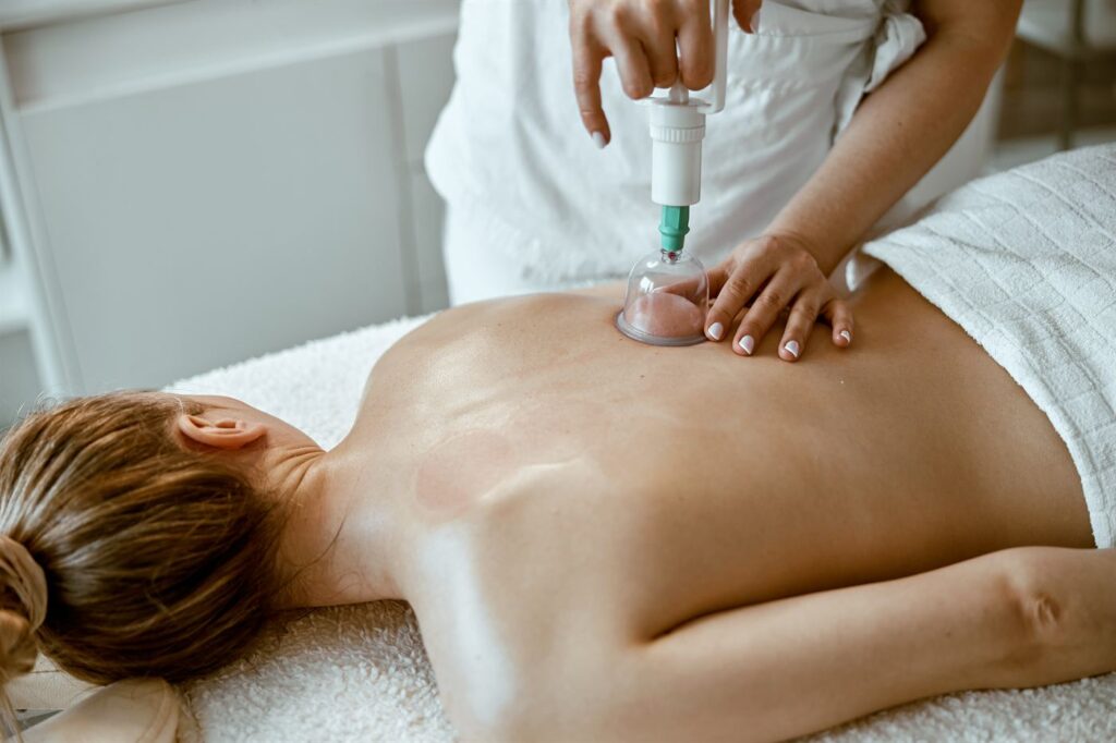 Praticien qui pose des ventouses de massage sous vide avec une pompe manuelle sur le dos d’une cliente